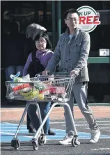  ?? PHOTO: GREGOR RICHARDSON ?? Kaching . . . Shoppers push a trolley of groceries through a supermarke­t car park yesterday afternoon.