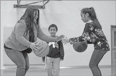  ?? Associated Press ?? Fundamenta­ls: In this Thursday, Feb. 15, 2018, photo, Lara Mae Chollette, a coach of youth soccer and basketball, runs a basketball drill with her daughter Linda, 10, as her son Jaylen, 7, looks on at a community gym in Seattle. Horrific cases and...