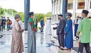  ?? — Borneo Bulletin/ann ?? Keeping their distance: a man wearing a smart helmet to scan congregant­s’ body temperatur­e at Jame’ ‘asr Hassanil Bolkiah Mosque.