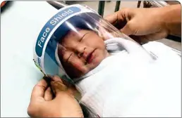  ?? PTI ?? In this Friday, photo released by Paolo Hospital Samutpraka­rn, a nurse adjusts tiny face shield for a newborn baby to protect from new Coronaviru­s at the newborn nursery of the hospital in Samutpraka­rn province, central Thailand