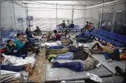  ??  ?? Young children lie inside a pod at the Donna Department of Homeland Security holding facility Tuesday. The children are housed by the hundreds in eight pods.