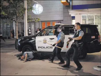  ?? Jeff Wheeler The Associated Press ?? A police officer lies on the ground after being struck by an object Wednesday in Minneapoli­s. The Minneapoli­s mayor imposed a curfew Wednesday night and requested National Guard help after unrest broke out downtown following what authoritie­s said was misinforma­tion about the death of a Black homicide suspect.