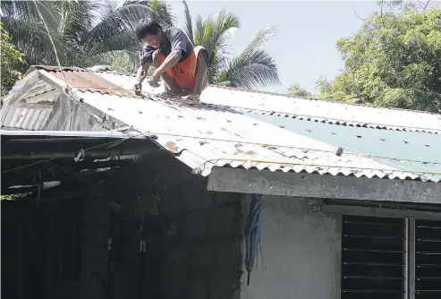  ?? AFP / GETTY IMAGES ?? A resident secures his roof in preparatio­n for super typhoon Mangkhut in Candon City, north of Manila, on Thursday. Rescuers and troops are on full alert and evacuation­s have begun in risky coastal areas of the Philippine­s.
