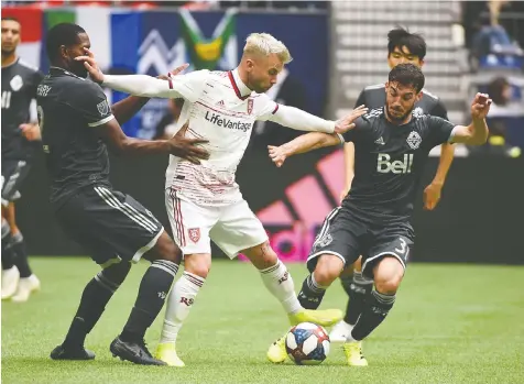  ?? — USA TODAY SPORTS ?? Real Salt Lake midfielder Albert Rusnak tries to stiff-arm both Vancouver Whitecaps defender Doneil Henry, left, and midfielder Russell Teibert during Sunday’s regular season-ending game at B.C. Place Stadium.