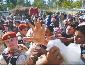  ?? "1 1)050 ?? Soldiers distribute Russian humanitari­an aid at the check-point of the de-escalation zones near Homs, Syria.