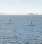  ??  ?? Sarah Lent (left) and Sam Petrie paddleboar­d while enjoying the view near the shores in Sausalito.