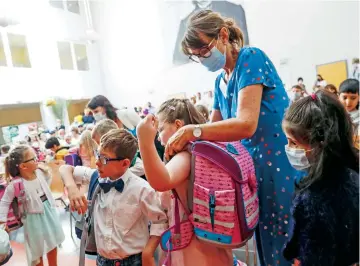  ??  ?? Una cuidadora ayuda a sus alumnos con sus mochilas en Schwerin, Alemania, el pasado 1 de agosto. Algunos estados federados obligan a los estudiante­s a llevar tapabocas en los pasillos y en el baño de los centros educativos.