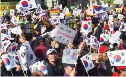  ?? — AFP ?? SEOUL: Supporters of South Korean President Park Geun-Hye wave the national flags during a pro-Park rally at Seoul station in Seoul.