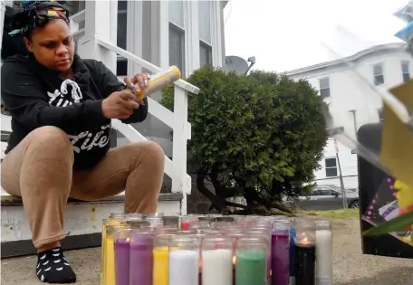  ??  ?? LIGHT A CANDLE FOR HER: Syon Williams lights a candles for her ‘Nana,’ 73-year-old Delois Brown. Williams was not a blood relative but lived in the same apartment house and was very close to Brown, she said.