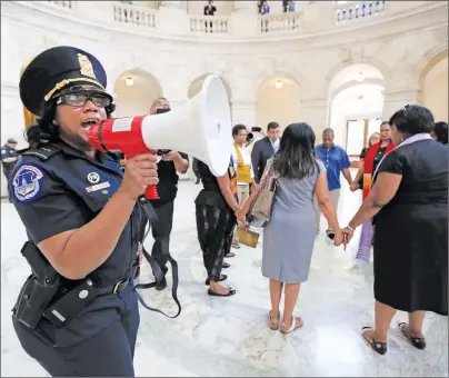  ?? AP PHOTO ?? A U.S. Capitol Police officer gives the warning speaking through a bullhorn to a group of Black minister gathered to protest on Capitol Hill in Washington Tuesday demanding Congress to “reject both the immoral budget proposed by the Trump...