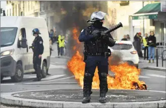  ??  ?? A French riot police officer stands next to a burning barricade during a demonstrat­ion against French government’s education reforms in Bordeaux yesterday.