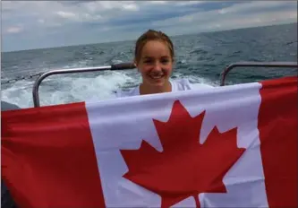  ?? HO, THE CANADIAN PRESS ?? Emily Epp holds a Canadian flag on board a boat on the English Channel. Epp, a 17-year-old from Kelowna, B.C., swam the English Channel and raised more than $40,000 for a children’s hospice.