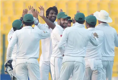  ?? — AFP ?? Pakistani bowler Rahat Ali (third left) celebrates with team-mates after the dismissal of the West Indies’ batsman Marlon Samuels (unseen) on the second day of the second Test between Pakistan and West Indies at the Sheikh Zayed Cricket Stadium in Abu...