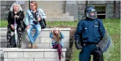  ?? AP ?? A young girl takes a photo on her cell phone beside a police officer in riot gear as he stands watch ahead of a planned G7 protest in Quebec City.