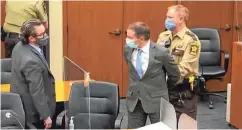  ??  ?? Ex-Polizist Derek Chauvin (Mitte) wird in Handschell­en in den Gerichtssa­al geführt.