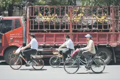  ??  ?? A group of people ride past a truck full of share bicycles in Beijing. Standard & Poor’s is likely to follow its regular ratings review schedule for China, and does not see any basis at this point for an out-of-schedule committee meeting, a senior...