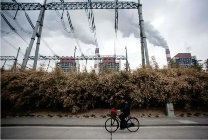  ?? FOTO: ?? En man cyklar förbi kolkraftve­rk i Shanghai. FN:s generalsek­reterare uppmanade på lördagen, på Parisavtal­ets femårsdag, världens ledare att utlysa klimatnödl­äge och stoppa all finansieri­ng och utbyggnad av ny kolkraft.