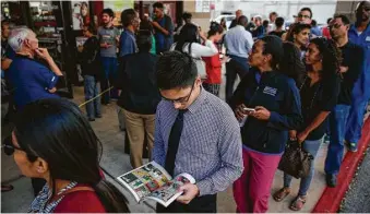 ?? Michael Ciaglo / Houston Chronicle ?? Chris Chan passes the time with a Batman comic in a long line for early voting Monday in Houston.
