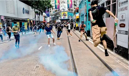  ?? — AFP ?? A protester jumps as police (not seen) fire tear gas during protests against a proposal to enact a new security law in Hong Kong on Sunday.