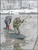  ??  ?? Wildlife officer Ghulam Mohiuddin Dar (right) along with Ahmad struggles to row their boat on the frozen surface of a wetland.