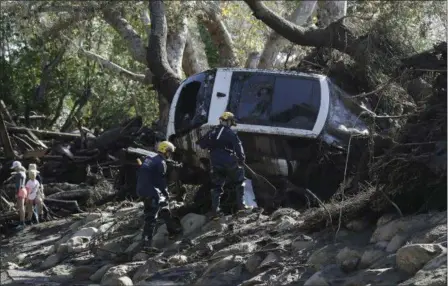  ?? MARCIO JOSE SANCHEZ — THE ASSOCIATED PRESS ?? Members of the Los Angeles County Fire Department Search and Rescue crew work on a car trapped under debris in Montecito Wednesday. Dozens of homes were swept away or heavily damaged and several people were killed Tuesday as downpours sent mud and...