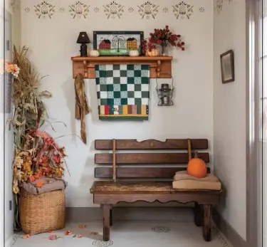  ??  ?? The entry hall, appointed with stencils on the walls and floor, handcrafte­d furniture, baskets and quilts, draws visitors into the Tweedies’ inviting home. Cornstalks, dried flowers and pumpkins lend the space an autumnal air.