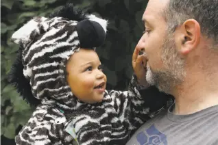  ?? Craig Lee / Special to The Chronicle ?? Kai Broadwater, 1½, in his zebra costume, enjoys the Oakland Boo at the Zoo event with his father, Noah Broadwater.