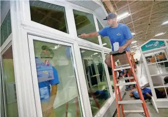  ?? MIKE DE SISTI / MILWAUKEE JOURNAL SENTINEL ?? Adam Karas and Jeff Schnur (inside display), of S.E. Wisconsin Sunrooms in Wind Lake, clean windows on a four-season sunroom Wednesday at the company’s display for the Milwaukee NARI Home & Remodeling Show. For more photos, see jsonline.com/business.