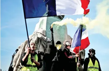  ?? — Reuters photo ?? Protesters wearing yellow vests hold French flags and a safety flare during a demonstrat­ion by the ‘yellow vests’ movement in Paris.