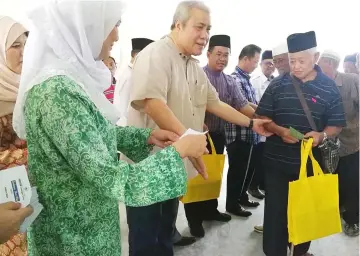  ??  ?? Awang Tengah (front, second left), with Dayang Morliah on his right, presents Hari Raya goodies to a local elderly citizen.