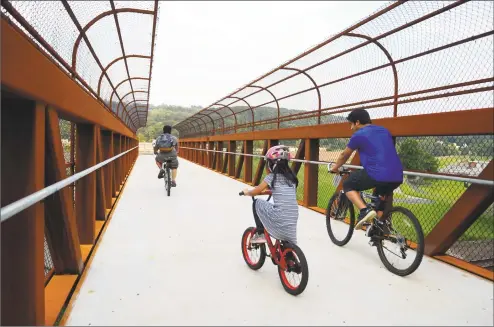  ?? Christian Abraham / Hearst Connecticu­t Media ?? A family crosses the new bridge connecting the river walk path off of Pershing Drive in Ansonia on Wednesday.