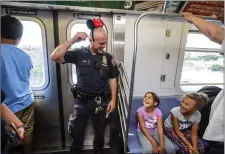  ??  ?? Capturing a light-hearted moment between a New York cop and children riding the subway.