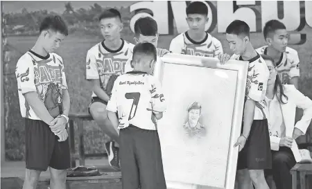  ?? VINCENT THIAN/AP ?? Coach Ekapol Chantawong, left, and members of the Wild Boars soccer team show their respect with a portrait of Saman Gunan, the retired Thai diver who died during their rescue, at a news conference in Chiang Rai, Thailand.