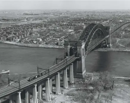  ??  ?? Left: Looking like a toy on the massive bridge, PC GG1 4873 begins the 1.2percent descent from the main span with a Washington–Boston train. Amtrak is 12 days ahead.
Right: A northward view shows the Hell Gate Bridge (foreground), the four-span deck-truss Little Hell Gate Bridge over filled land, and the twospan through-truss Bronx Kill Bridge.