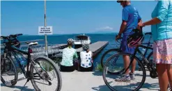  ?? — AP photos ?? Bicyclists wait to get on a special ferry across a cut in an abandoned railroad causeway between the Vermont mainland and the Lake Champlain islands.