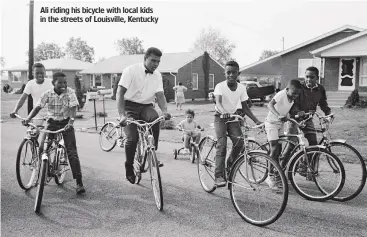  ??  ?? Ali riding his bicycle with local kids in the streets of Louisville, Kentucky