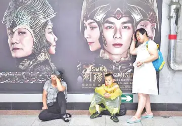  ??  ?? People rest in front of posters for the movie ‘Asura’ at a subway station in Beijing.