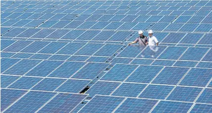  ?? ANTARA FOTO/WIDODO S JUSUF VIA REUTERS ?? PLN officials stand between solar cell panels at the largest solar power plant at Oelpuah village in Kupang in this file photo.