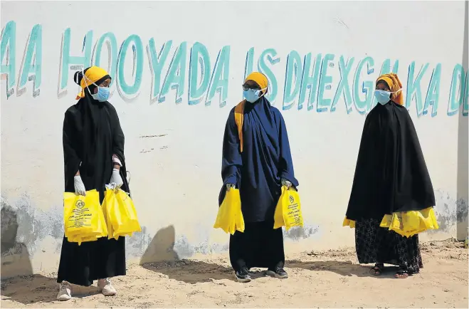  ?? Picture: Sadak Mohamed/Anadolu Agency via Getty Images ?? Volunteers distribute cleaning supplies and advice on protection against the coronaviru­s in a refugee camp in Mogadishu, Somalia, this week.