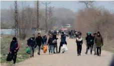 ??  ?? Migrants and refugees carrying their belongings walk along the Turkish-Greek border, in Edirne, yesterday.