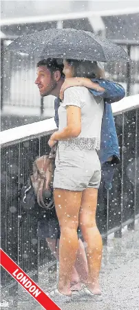  ??  ?? Couple shelter under a brolly from Thames thunder