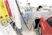  ?? Chuck Burton / Associated Press file ?? Lucy Perez of Charlotte, N.C., pumps gas at a station in Matthews, N.C. Prices for U.S. crude sank 13 percent from June 30 to Wednesday.