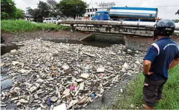 ?? ?? The aftermath: A man looking at the rubbish clogging up Sungai Nyuir near Jalan Chain Ferry in Butterwort­h.