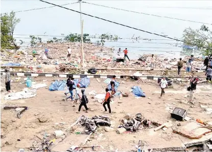  ?? AFP ?? La gente camina entre los cadáveres de las víctimas en la ciudad de Palu.