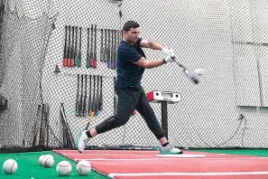  ?? (AP Photo/Ross D. Franklin) ?? A batter takes a swing inside a batting cage Feb. 16 at the Driveline facility in Scottsdale, Ariz. The batting informatio­n is read by a sensor device just to the right of the batter and the informatio­n is projected onto the screen in a different part of the cage area.