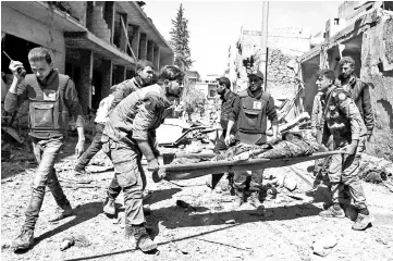  ??  ?? File photo show members of the Syrian Civil Defence (known as the White Helmets) and the Red Crescent remove the body of a civilian from the street following air strikes on Douma, the main town of Syria’s rebel enclave of Eastern Ghouta. — AFP photo