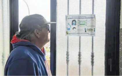  ?? TONI GUDIEL ?? Un vecino observa un cartel con las normas para evitar contagios, en un portal de Pablo Iglesias.