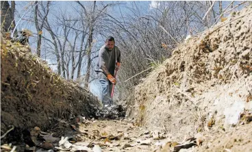  ?? LUIS SÁNCHEZ SATURNO/THE NEW MEXICAN ?? Lorenzo Duran of Nambé clears the Acequia de las Joyas on Friday. The annual spring ritual of cleaning acequias, which usually involves shovel-to-shovel contact and face-to-face interactio­n among neighbors or adjoining landowners, has been upended this year by social-distancing orders and concerns about the spread of COVID-19.