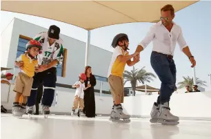  ?? Photos by Shihab ?? Tassilo Schwartz trains children during their first skate at the newly-installed synthetic ice rink at The Next Generation School in Barsha on Wednesday. Right, kids anxiously wait for their turn to experience the skating as they watch their peers...