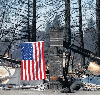  ?? AP PHOTO ?? An American flag hangs on a burned home, Sunday, in Santa Rosa, Calif. A state fire spokesman says it appears firefighte­rs are making good progress on deadly wildfires that started a week earlier, devastatin­g wine country and other parts of rural...